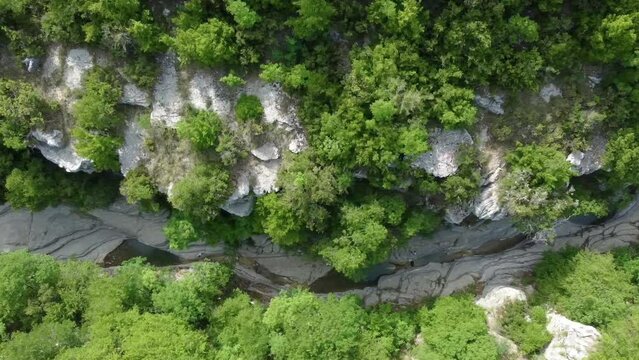 Aerial top-down view of the Papingo Rock Pools, also known as ovires, natural green water pools nestled in a small, smooth-walled gorge near the village of Papingo in Zagori region of Epirus, Greece.