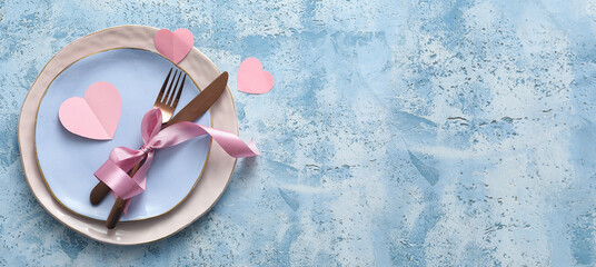 Beautiful table setting for Valentine's Day dinner on blue grunge background with space for text
