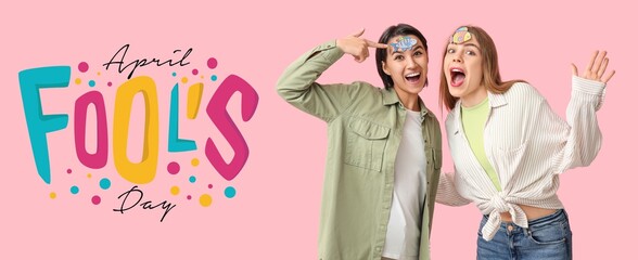 Banner for April Fools' Day with funny young women on pink background