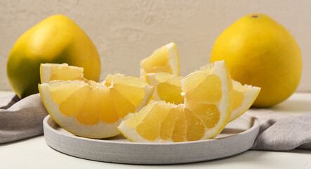 Plate of ripe sliced pomelo on table, closeup