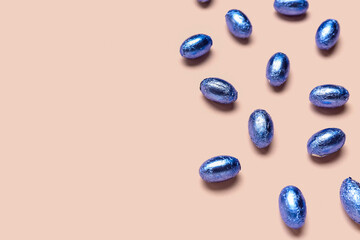Chocolate Easter eggs in color foil on color background
