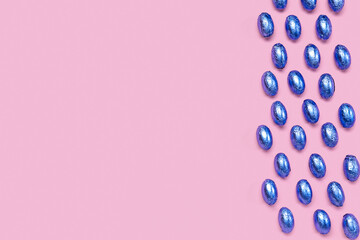 Composition with chocolate Easter eggs in color foil on pink background
