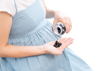 Pregnant woman wearing a blue dress takes supplement