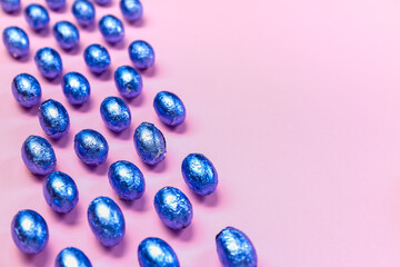 Composition with chocolate Easter eggs in color foil on pink background