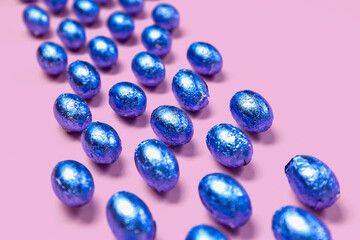 Composition with chocolate Easter eggs in color foil on pink background, closeup