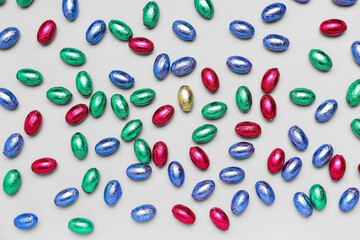 Chocolate Easter eggs in color foil on light background