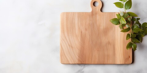 Top view of wooden cutting board on marble background, adorned with leaves on a linen napkin.