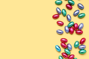 Chocolate Easter eggs in color foil on yellow background