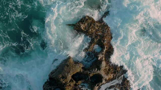 Aerial: Abstract texture of rough ocean surf crashing over rocks in slow motion. Muriwai, Auckland, New Zealand