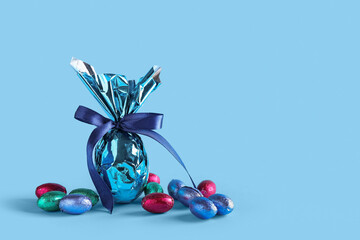 Sweet chocolate Easter eggs wrapped in foil on color background