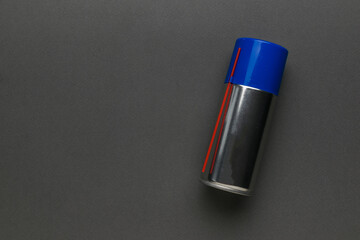 A closed aerosol can on a gray background.