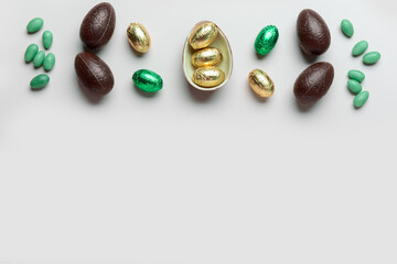 Sweet chocolate Easter eggs and candies on light background