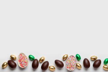 Sweet chocolate Easter eggs and candies on white background