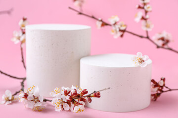 Podiums with blooming branches on pink background, closeup. Hello spring