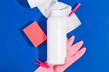 Blue background with cleaning tools for domestic house works. A white bottle of detergents, pink...