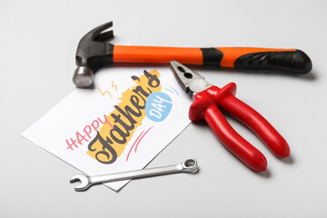 Card for Father's Day with work tools on grey background