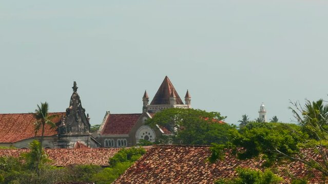 Roofs of buildings and grey sky. Action. Red roofs and green trees on a summer day.