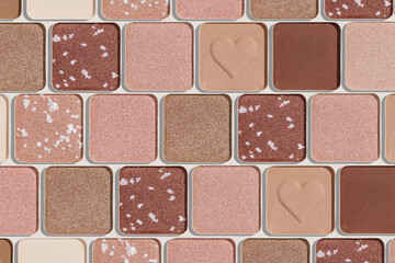 Fototapeta premium Minimal pattern of eye shadow beige tones swatches, monochrome photo background, eyeshadow with heart imprint, shiny natural shades powder makeup, square shape metal pack, beauty cosmetic texture