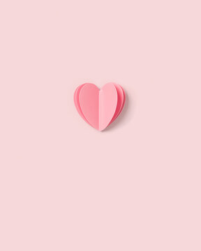 Pink paper heart on pink colored background. Minimal style flat lay, pastel monochrome colors, valentine card or wedding invitation. Handmade paper cut romantic concept, top view, close up