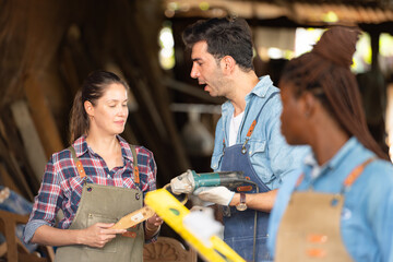 Portrait of carpenter female worker standing in front of colleague in workshop