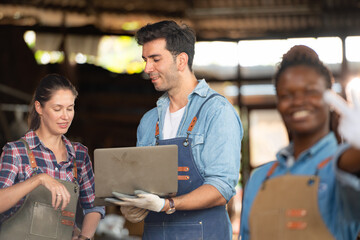 Portrait of carpenter female worker standing in front of colleague in workshop