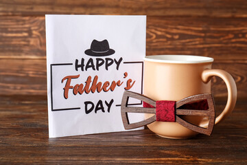 Card for Father's Day with cup and bow tie on wooden background