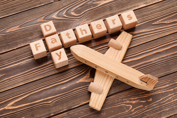Text FATHER'S DAY with toy airplane on wooden background