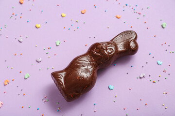 Chocolate Easter bunny and sprinkles on lilac background