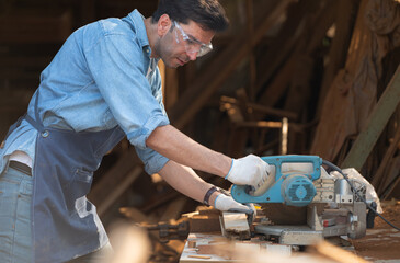 Portrait of a craftsman working with a circular saw at a wood workshop