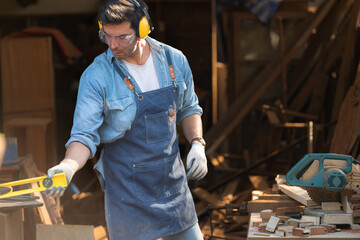 Portrait of a carpenter holding a spirit level in his workshop.