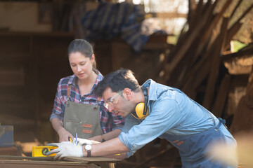 Carpenter and his assistant working together in a carpentry workshop