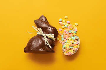 Chocolate Easter egg with sprinkles and bunny on orange background