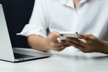 Woman in a white shirt uses a smartphone or tablet in a dark room. Holding hands. Black background....