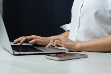 Fototapeta premium Woman uses a smartphone or tablet in a dark room. Holding hands. Black background. Home office. For work. For social media or searching for information