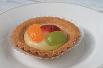 Fruit pie in paper cup in white plate on table