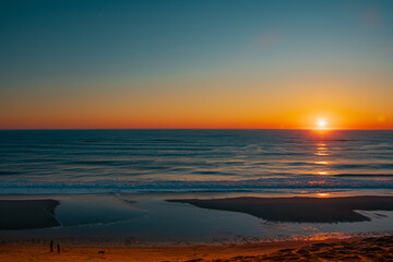 a couple and dog enjoying warm colors of a sunrise on a Cape Cod Beach