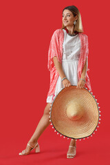 Pretty young woman with sombrero on red background