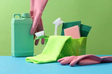 Brushes, sponges, rubber gloves and natural cleaning products in the basket decorated with an empty...