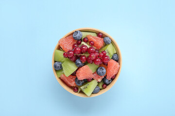 Bowl with fresh fruit salad on blue background