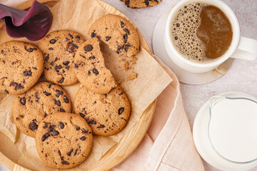 Tasty cookies with chocolate chips, milk and cup of coffee on white background