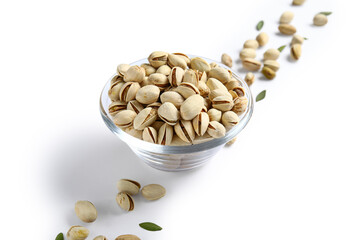 Glass bowl with tasty pistachio nuts and leaves on white background