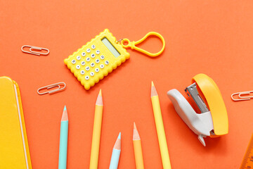 Colorful pencils with stationery on orange background