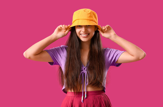 Stylish young woman in bucket hat on purple background