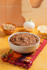 white plate full of refried bay beans, accompanied by cheeses and toast in Mexican cuisine