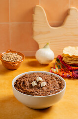 white plate full of refried bay beans, accompanied by cheeses and toast in Mexican cuisine