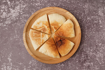 Plate with pieces of tasty pita bread on grey background