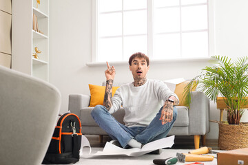 Young man having idea while assembling furniture at home - obrazy, fototapety, plakaty