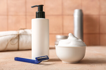 Set of shaving accessories on grunge pink table near tile wall
