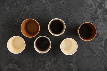 Paper cups of hot coffee on black background