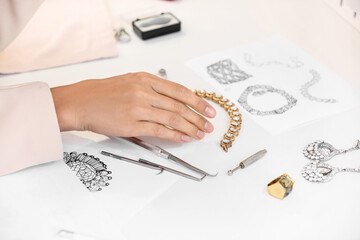 Female jewelry designer working with sketches of stylish accessories in office